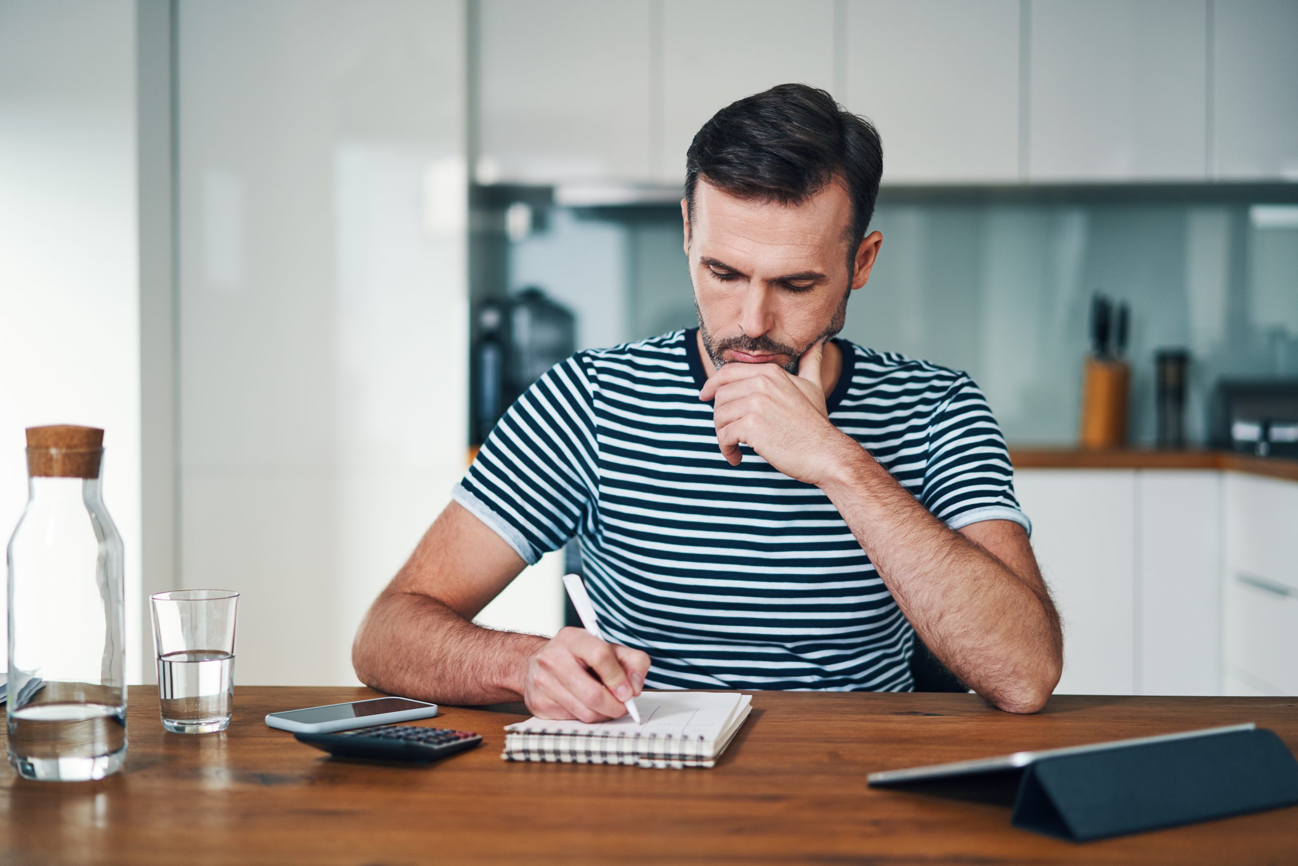 Comment effectuer une reconversion professionnelle avec INEAD. Homme réfléchissant en écrivant sur une feuille de papier sa réflexion.