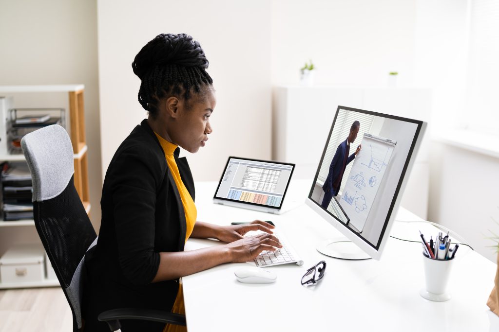 Jeune femme suivant un cours en ligne sur son ordinateur.