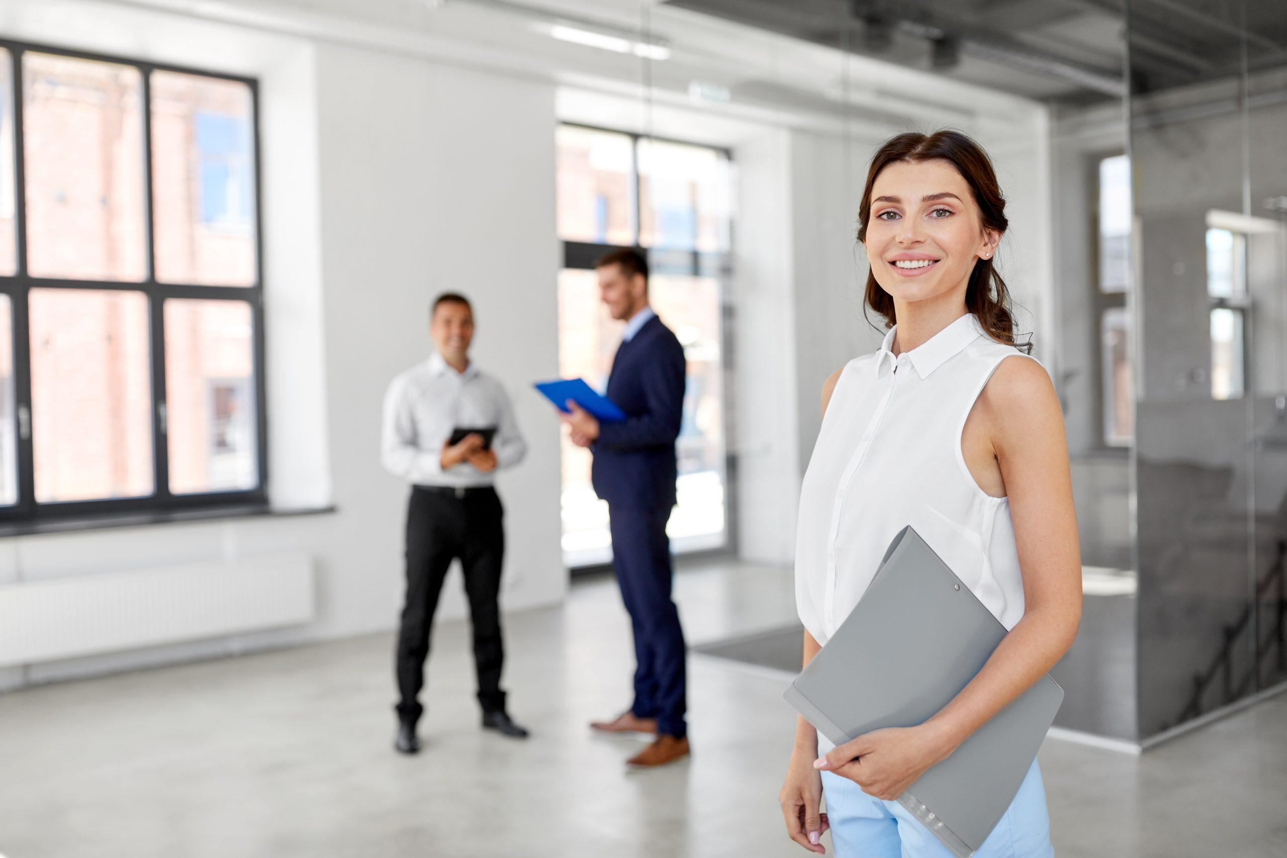 Bannière pour le domaine de formation en Immobilier. Conseiller en immobilier faisant faire une visite d'un bureau dans un immeuble.