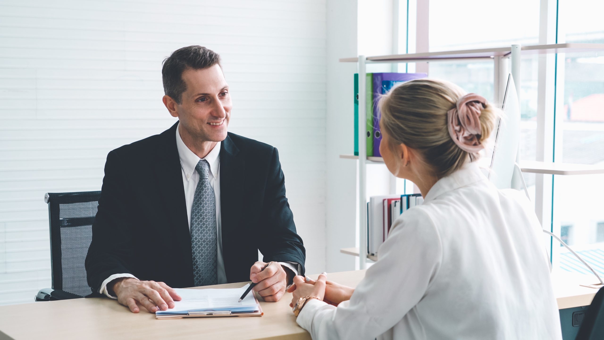 Recruter en alternance ou en apprentissage avec INEAD. Conversation professionnelle et souriante entre un manager réalisant un interview de recrutement avec une jeune femme candidate l'offre d'emploi proposée.