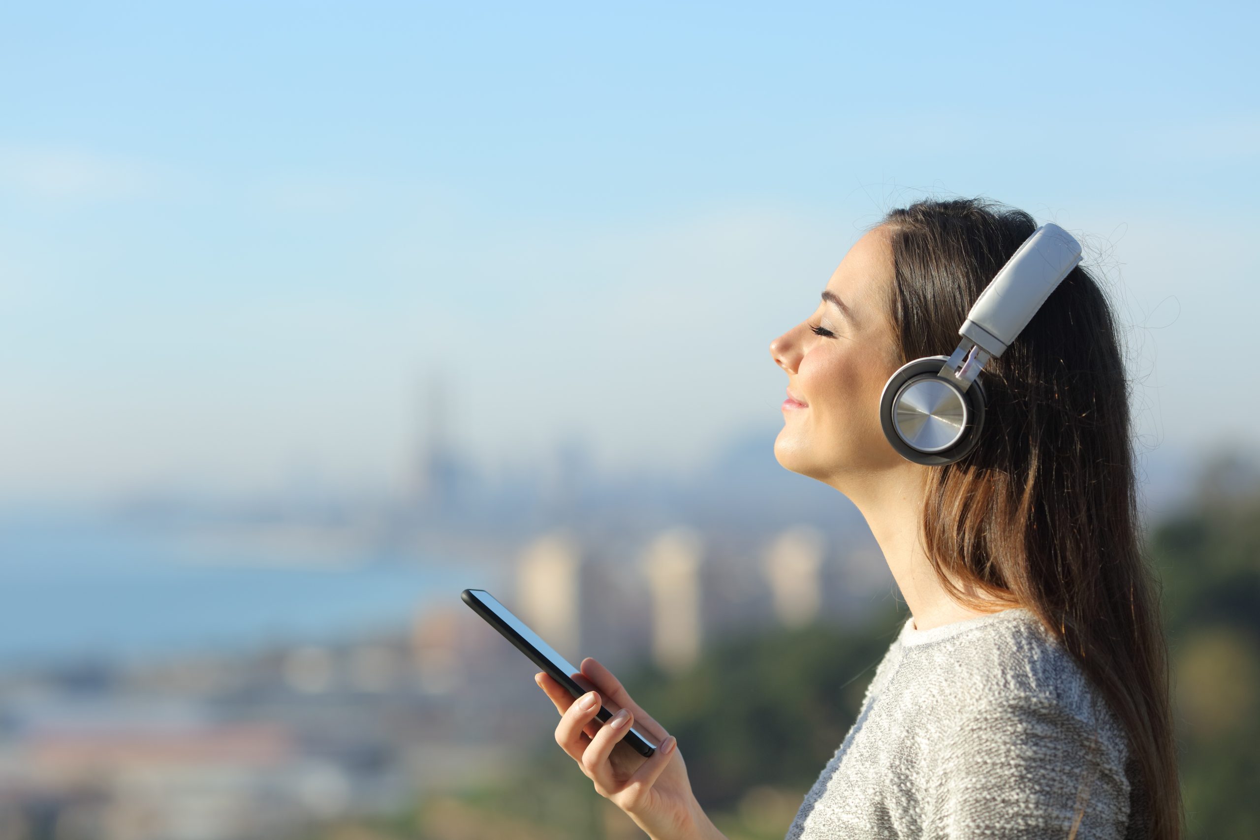 Présentation INEAD, école en ligne. Femme épanouie portant un casque et écoutant de la musique sur son mobile.