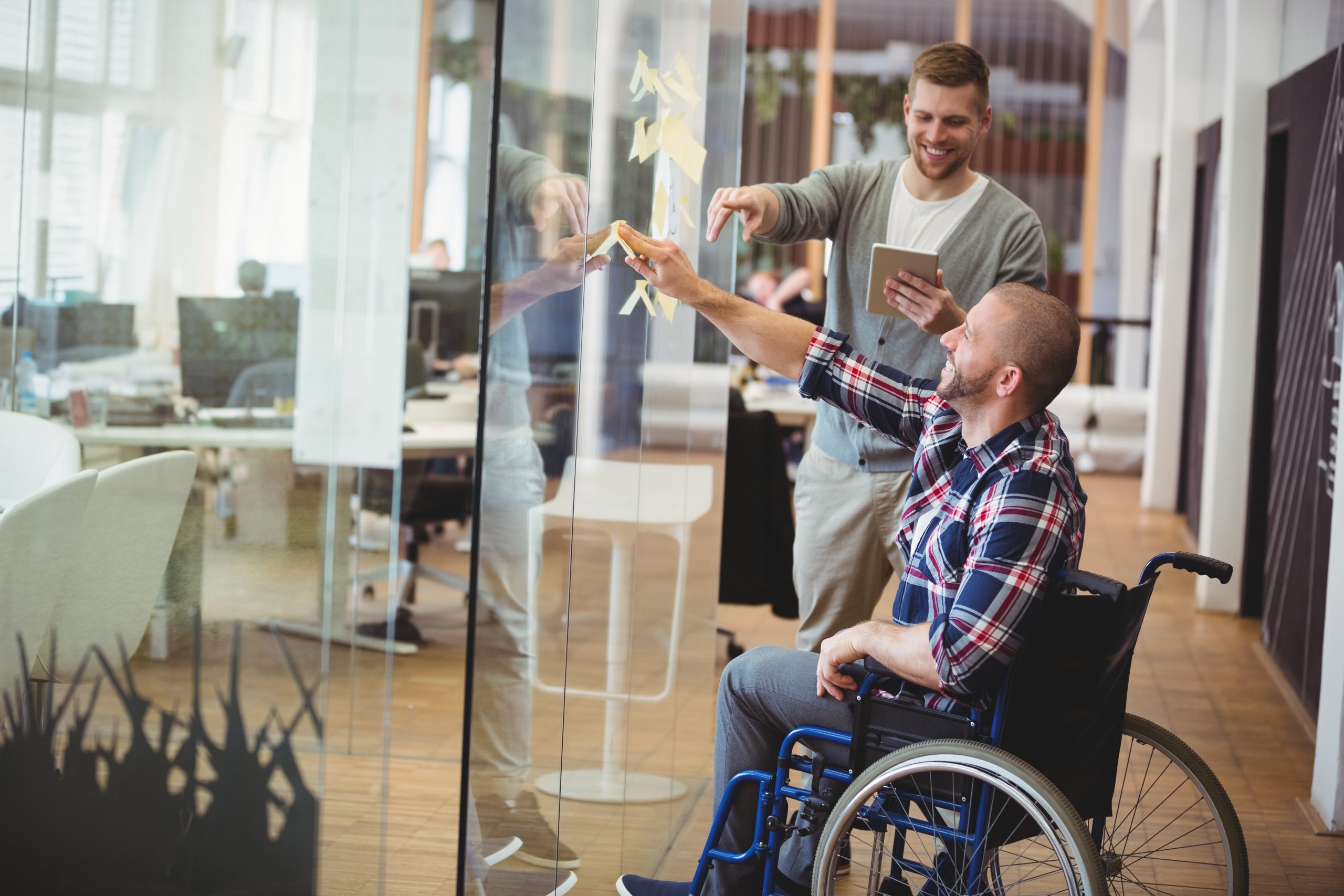 Solution de financement avec INEAd pour personne en situation de handicap. Collègue assistant un collègue en situation de handicap.