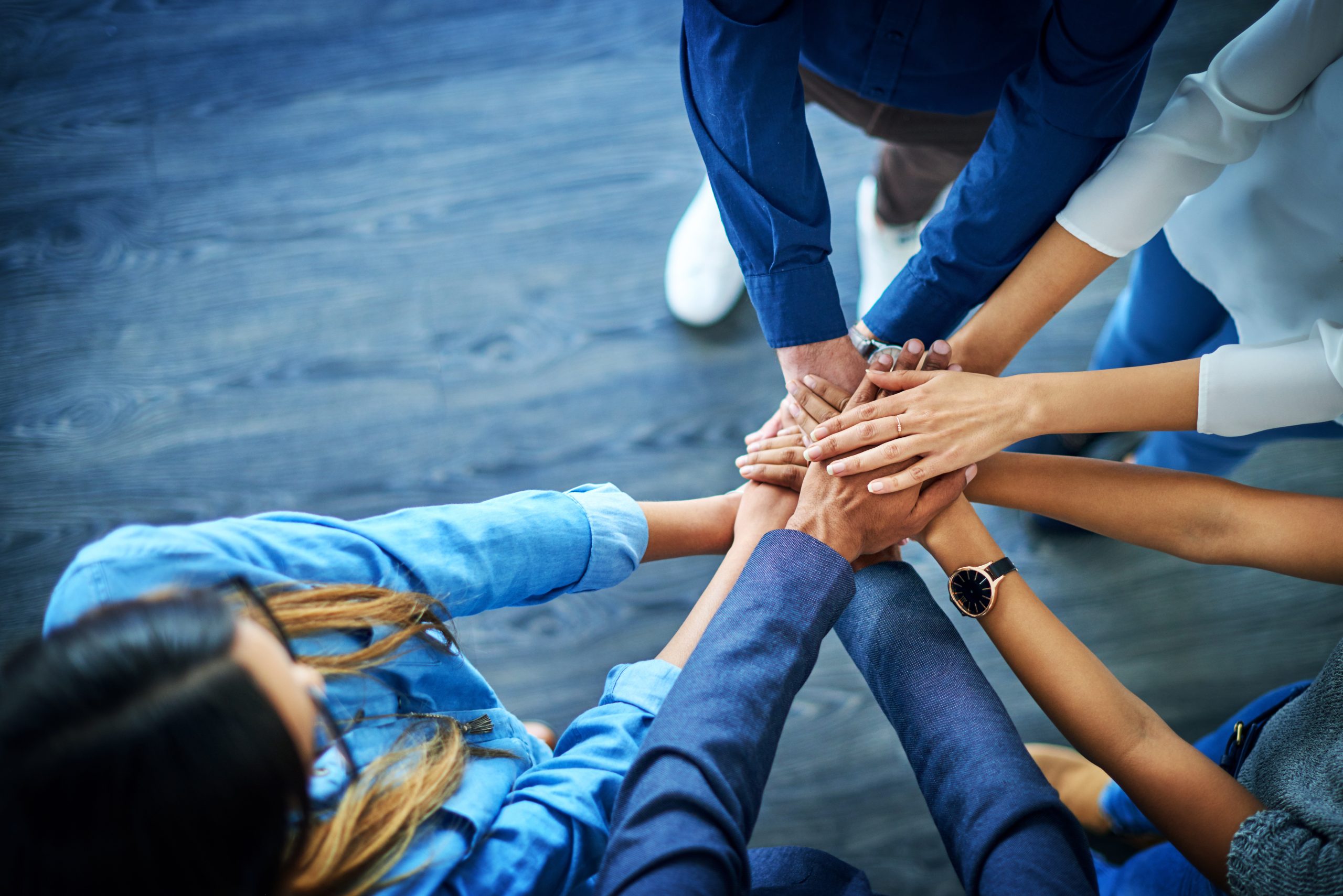 INEAD, école en ligne. Présentation Groupe Skolae. Mains jointes de plusieurs personnes d'une équipe en signe de réussite.