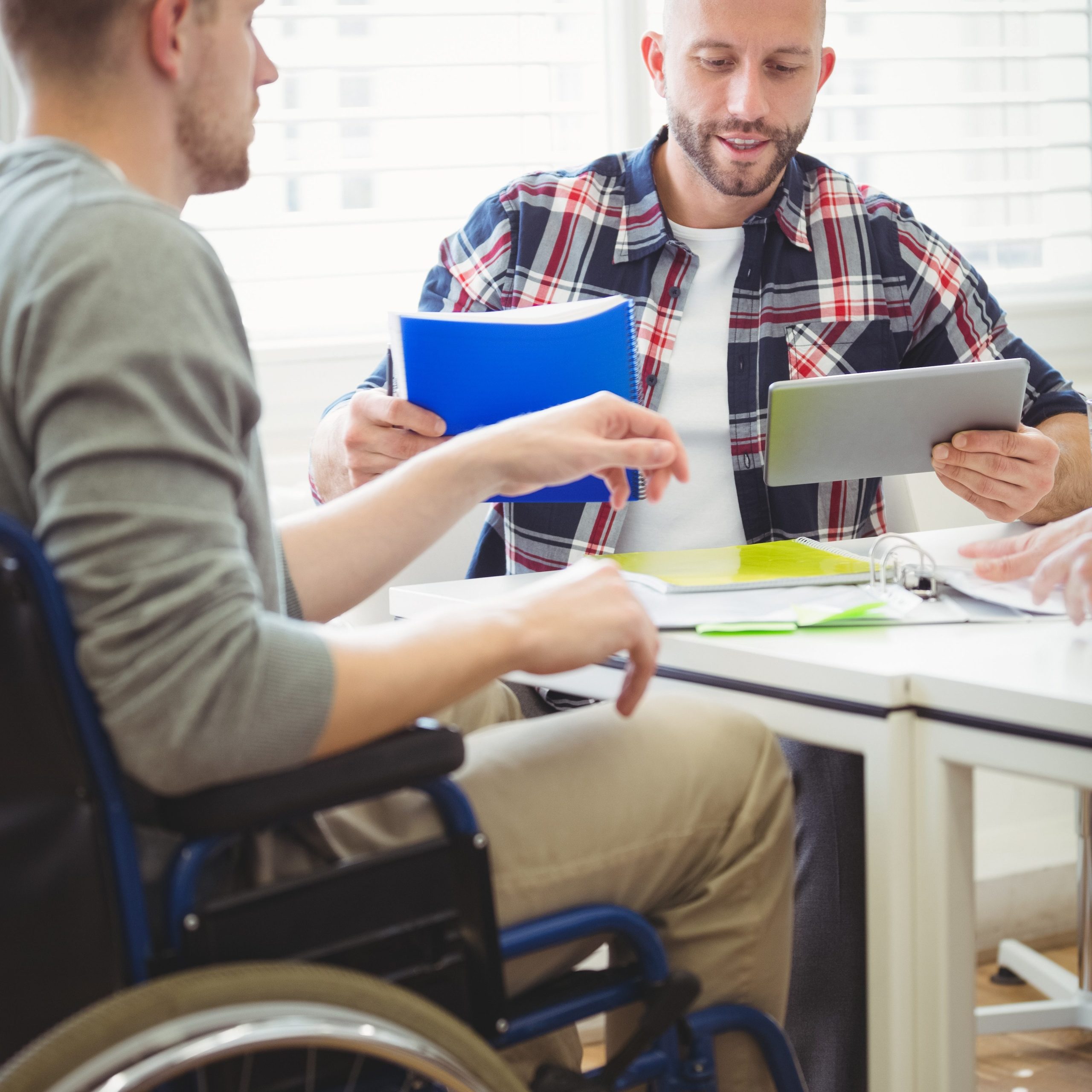 Handicap et accessibilité chez INEAD, école en ligne. Homme en situation de handicap assis dans un fauteuil roulant, discutant de son projet de formation en ligne avec un conseiller.